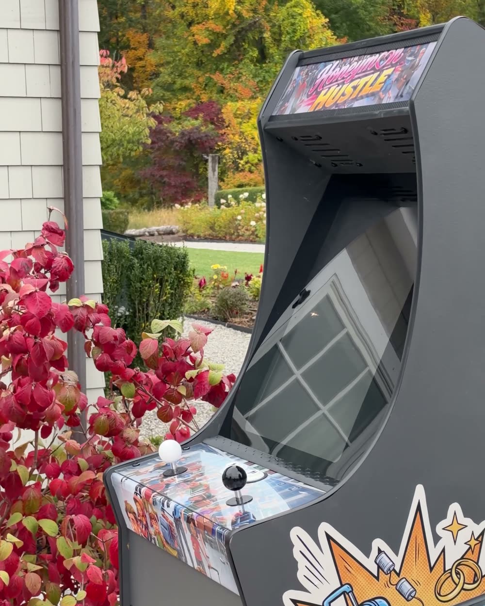 Honeymoon Hustle cabinet with its suitcase side art, framed by red autumn leaves