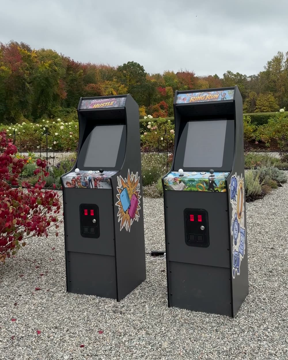 Honeymoon Hustle and Ring Run arcade cabinets side by side in a garden courtyard with fall foliage